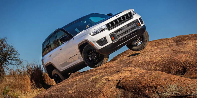 a white 2026 Jeep Grand Cherokee parked at an angle on a rocky outcropping 